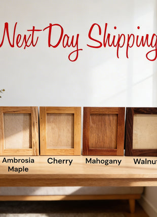 four different types of wooden picture frames arranged on a wooden table, with a vase of greenery and a window in the background.