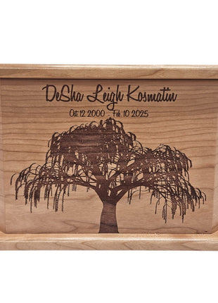 A wooden box with a tree engraved on it, featuring the text "DeSha Leigh Kosmatin" and the date "Oct 12 2000 - 10 10 2005".