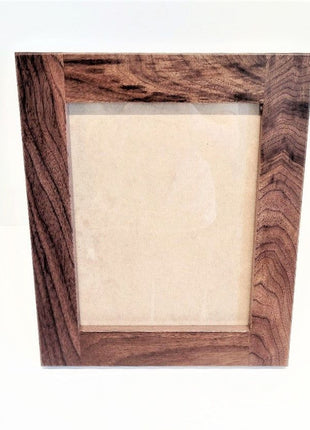A wooden picture frame with a light-colored interior, placed against a white background.