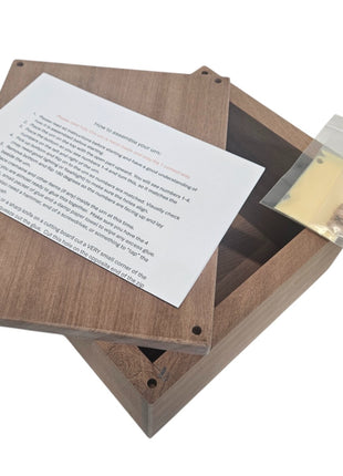 a wooden box with a piece of paper inside, and a small package is visible next to the box.