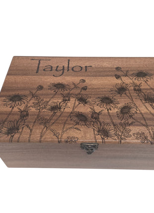 A wooden box with a floral design and the name "Taylor" engraved on it.